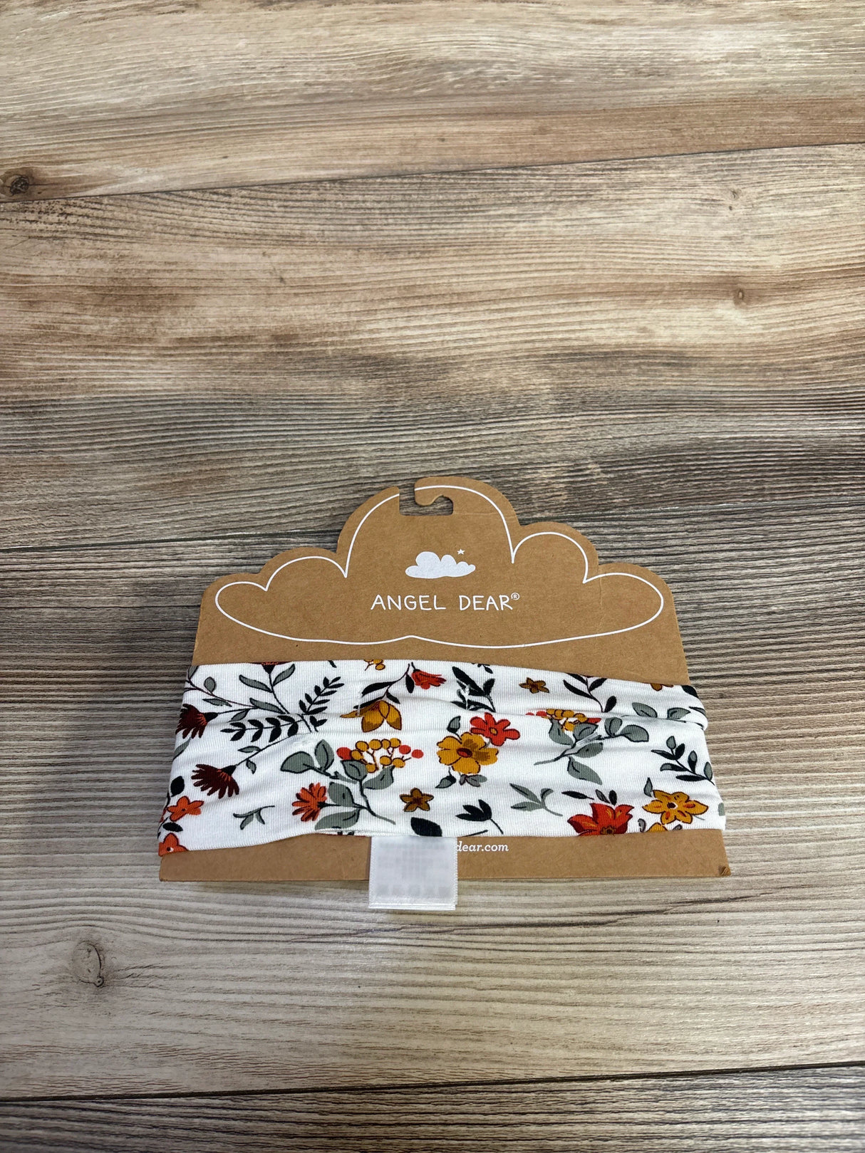 Angel Dear floral baby headband with orange, yellow, and green flowers on white fabric, displayed on kraft paper packaging