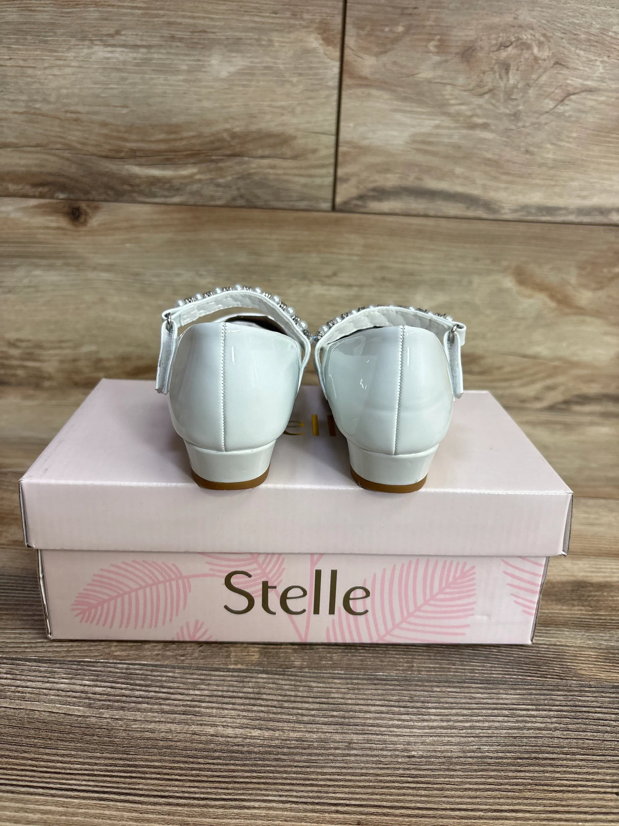 White patent leather girls' dress shoes with pearl strap detail on pink Stelle shoe box