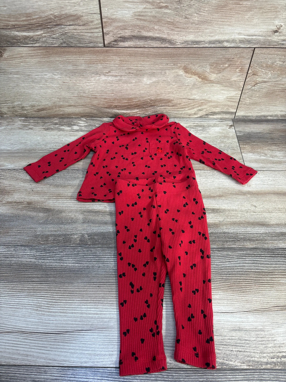 Flat lay of Baby Gap 2pc shirt and pants set showcasing red ribbed fabric and black heart print on wood flooring