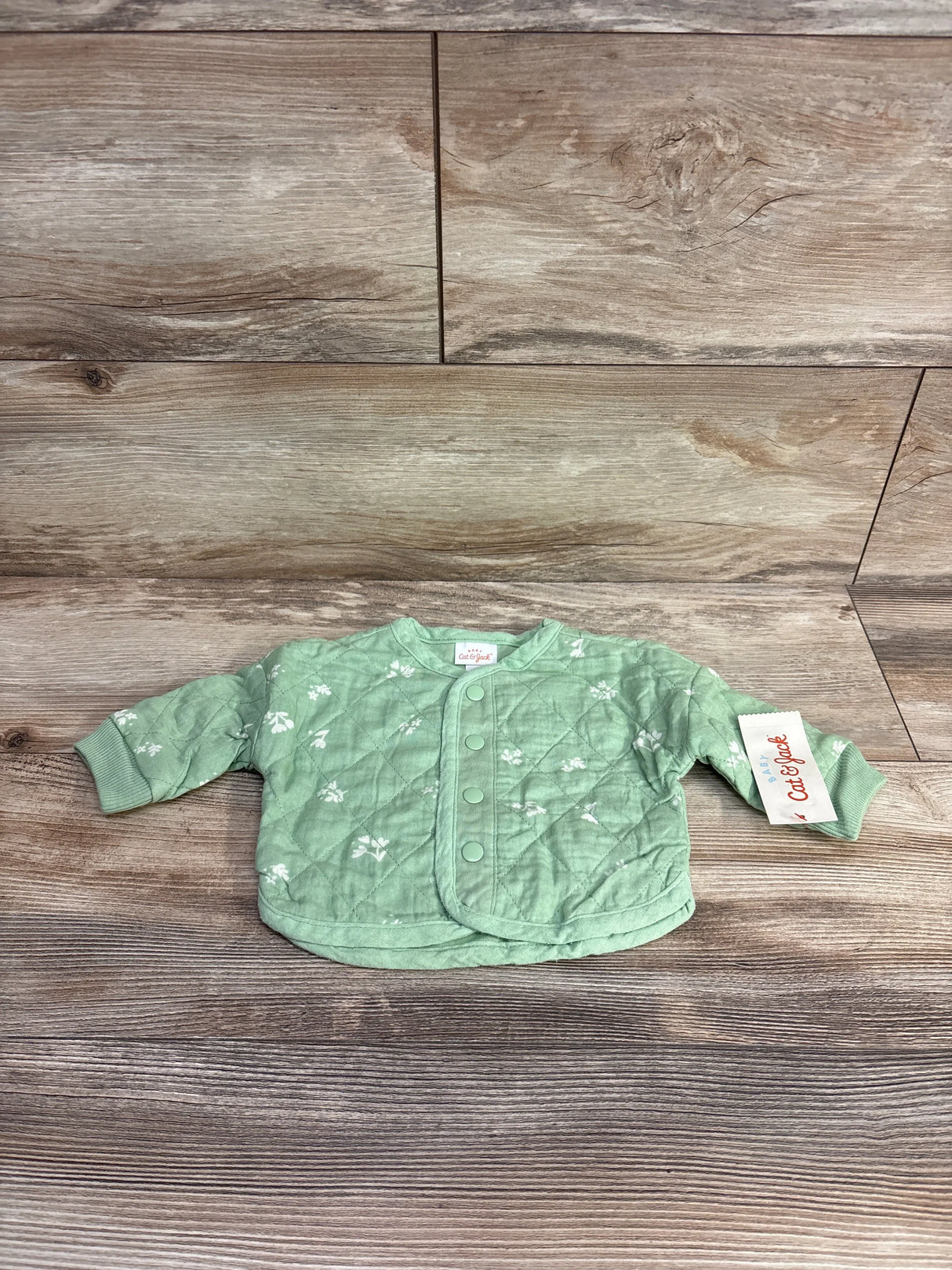 Light green quilted baby jacket with floral print, snap buttons, and cuffed sleeves