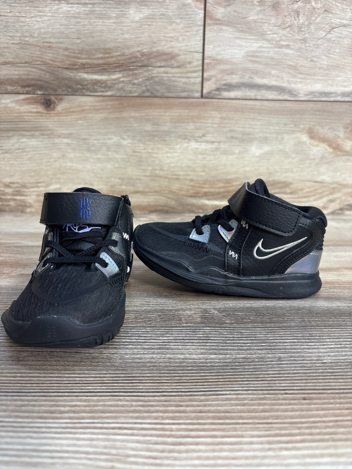 Black Nike Kyrie basketball toddler shoes with velcro straps on wood background