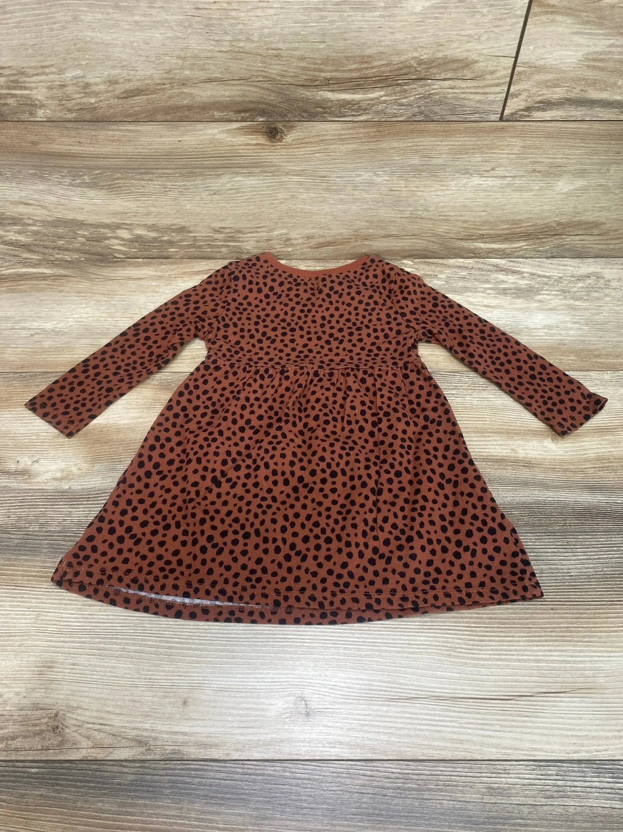 Flat lay of brown cheetah print toddler dress size 2T showing long sleeves and gathered skirt on wood background