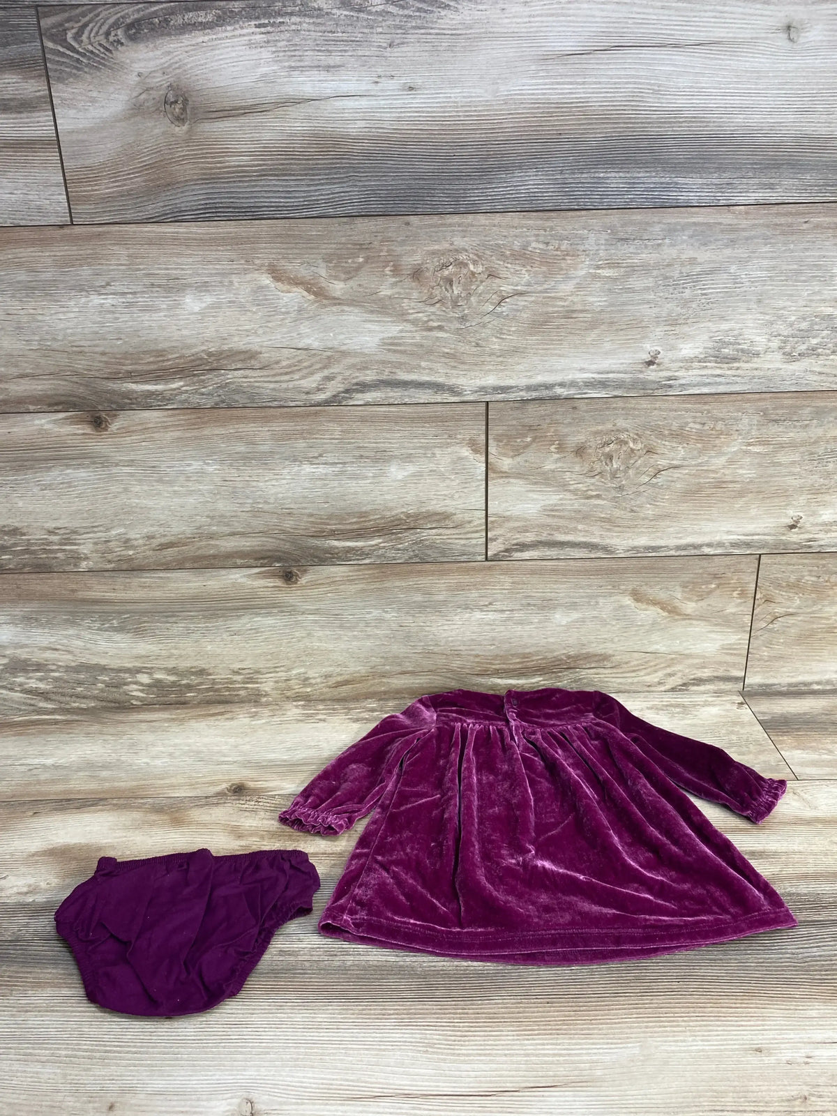 Plum velvet long sleeve baby dress with matching diaper cover on wood background