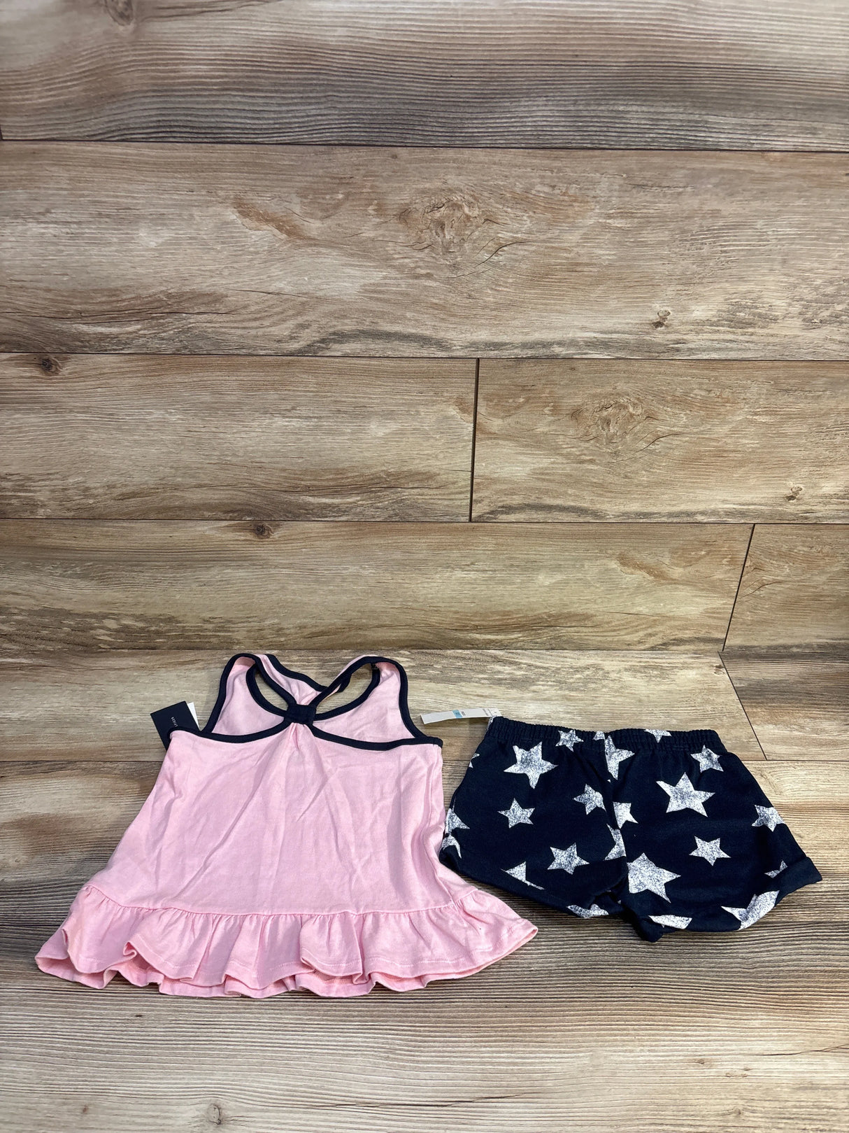 Front view of toddler 2 piece set, pink peplum tank with navy trim and ruffle hem and navy star print shorts, size 5T