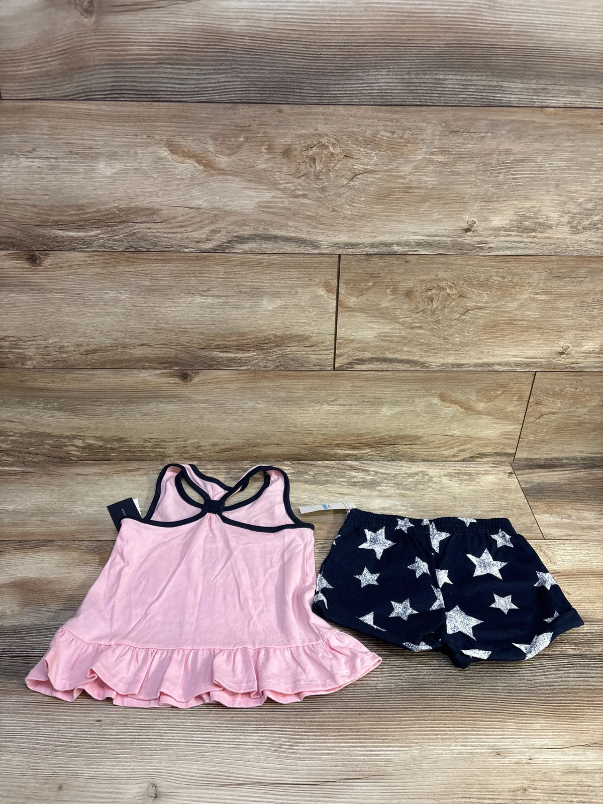 Front view of toddler 2 piece set, pink peplum tank with navy trim and ruffle hem and navy star print shorts, size 5T