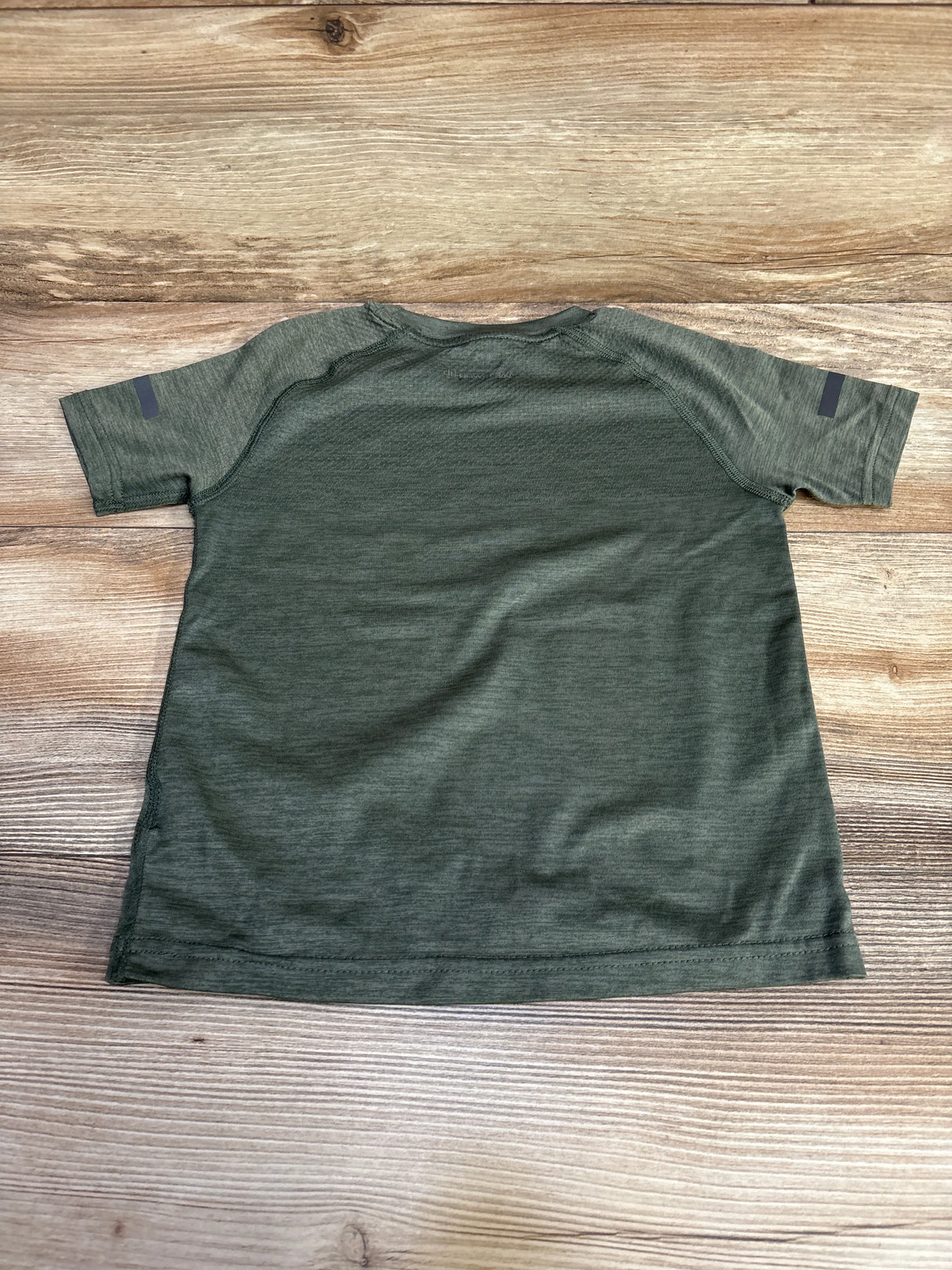 Olive green short sleeve athletic shirt on wood background, back view