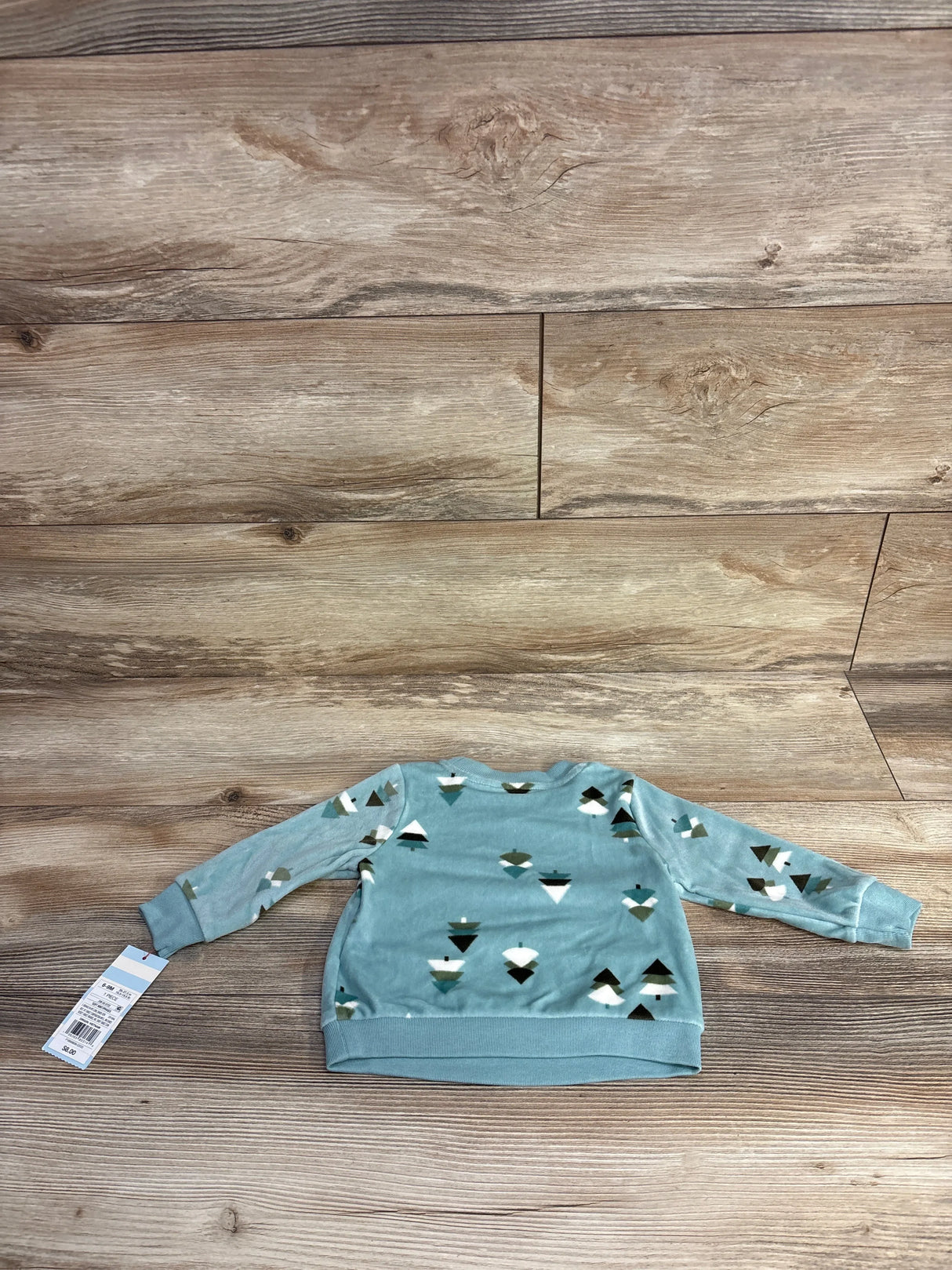 Blue long sleeve toddler shirt with geometric tree print on wood background