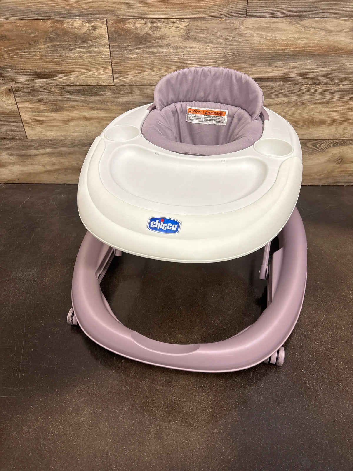 Front view of Chicco Mod walker in lavender showcasing padded seat, tray, cup holders, and wheels with wood floor background