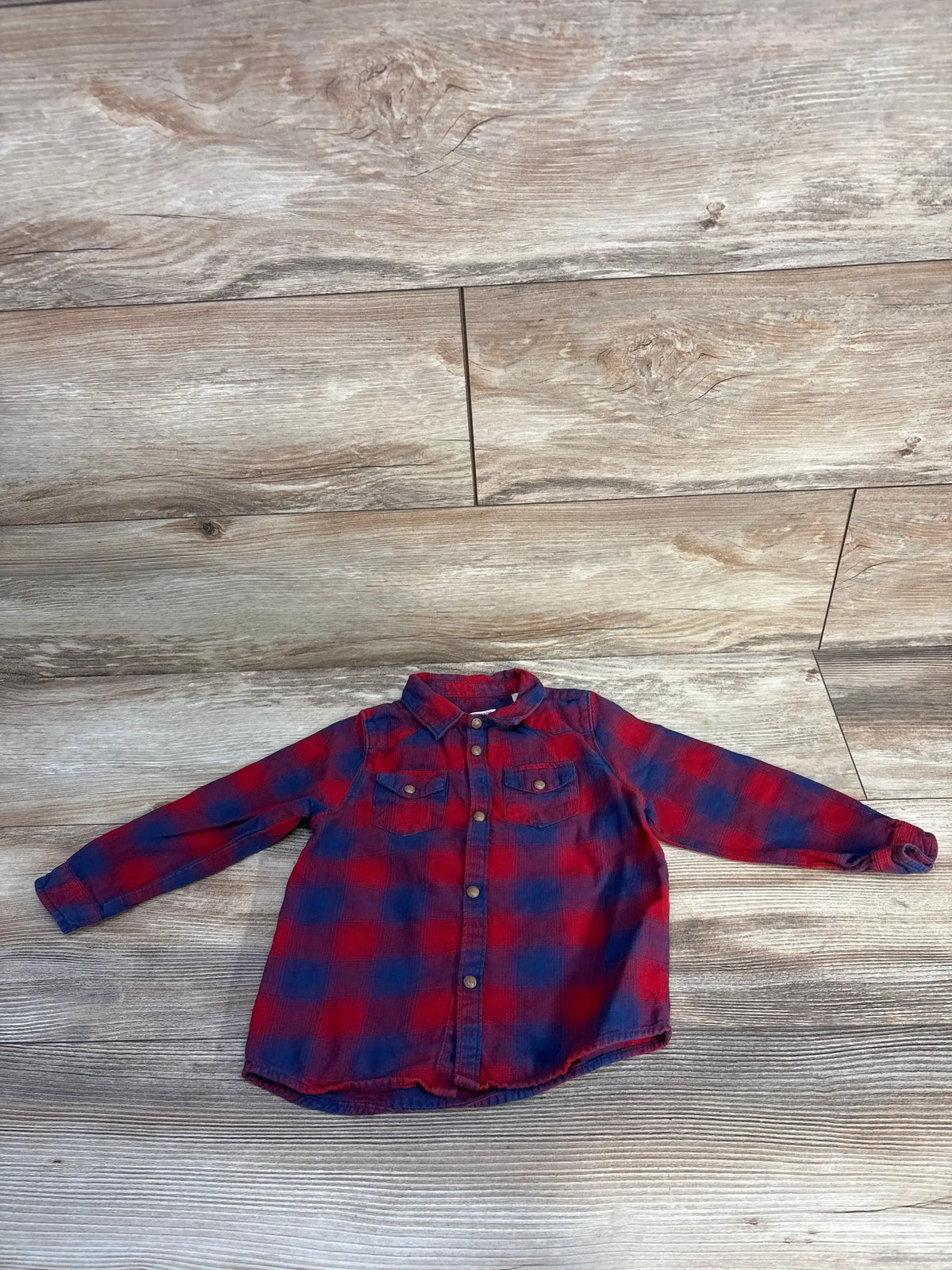 Red and blue plaid flannel shirt with buttons on wood background