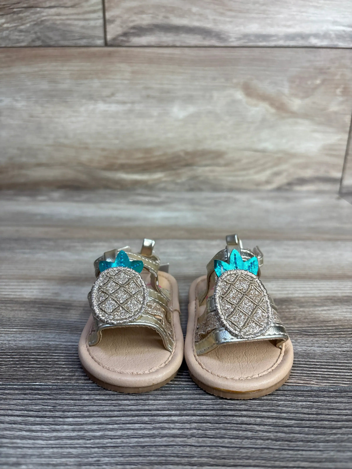 Front view of NEW 143 Girls Pineapple Sandals sz 1c showcasing metallic pineapple appliques with a wood-grain background
