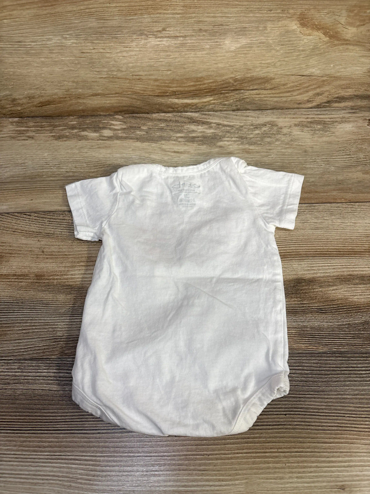 Back view of Garb I’m A Little Rebel UNLV bodysuit showcasing its white short-sleeved design on a wood-grain surface
