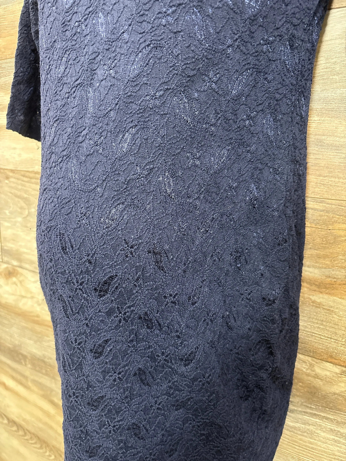Close-up of Pink Blush navy maternity fitted dress showing lace texture and 3/4 sleeve against a wood background