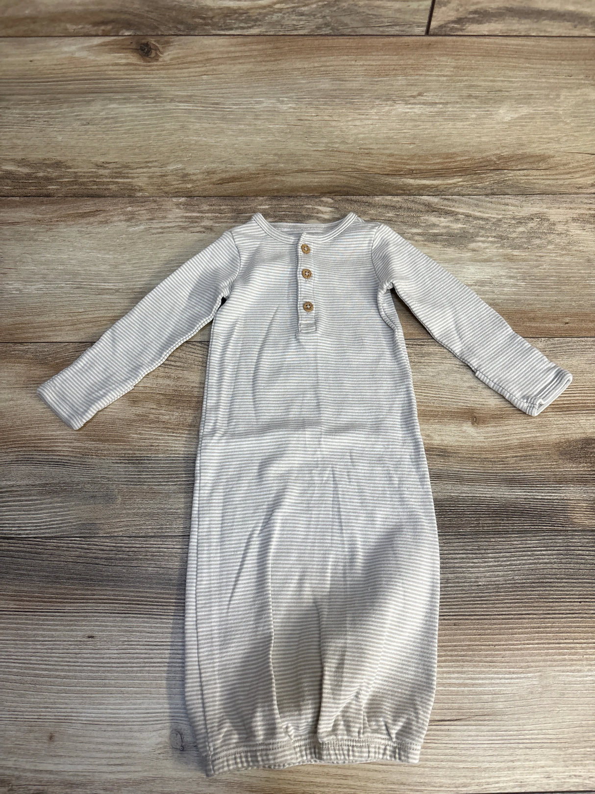 Striped baby onesie with buttons, soft fabric, laid on wooden surface