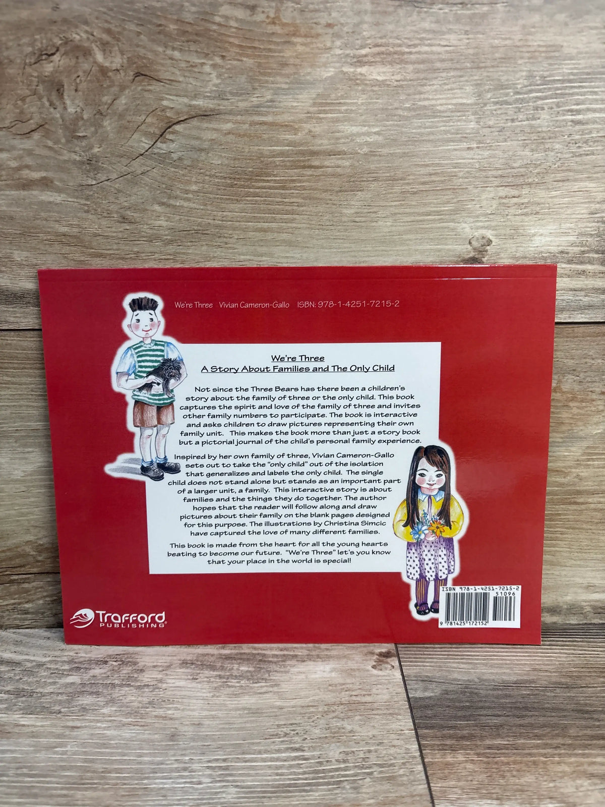 Back cover of We’re Three paperback book showing illustrated children and interactive family story description on red cover with wooden background