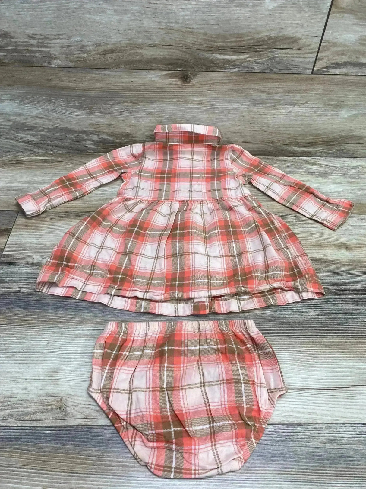 Flat lay of Carter's pink-brown plaid long-sleeve baby dress with gathered skirt and matching bloomers on wood background