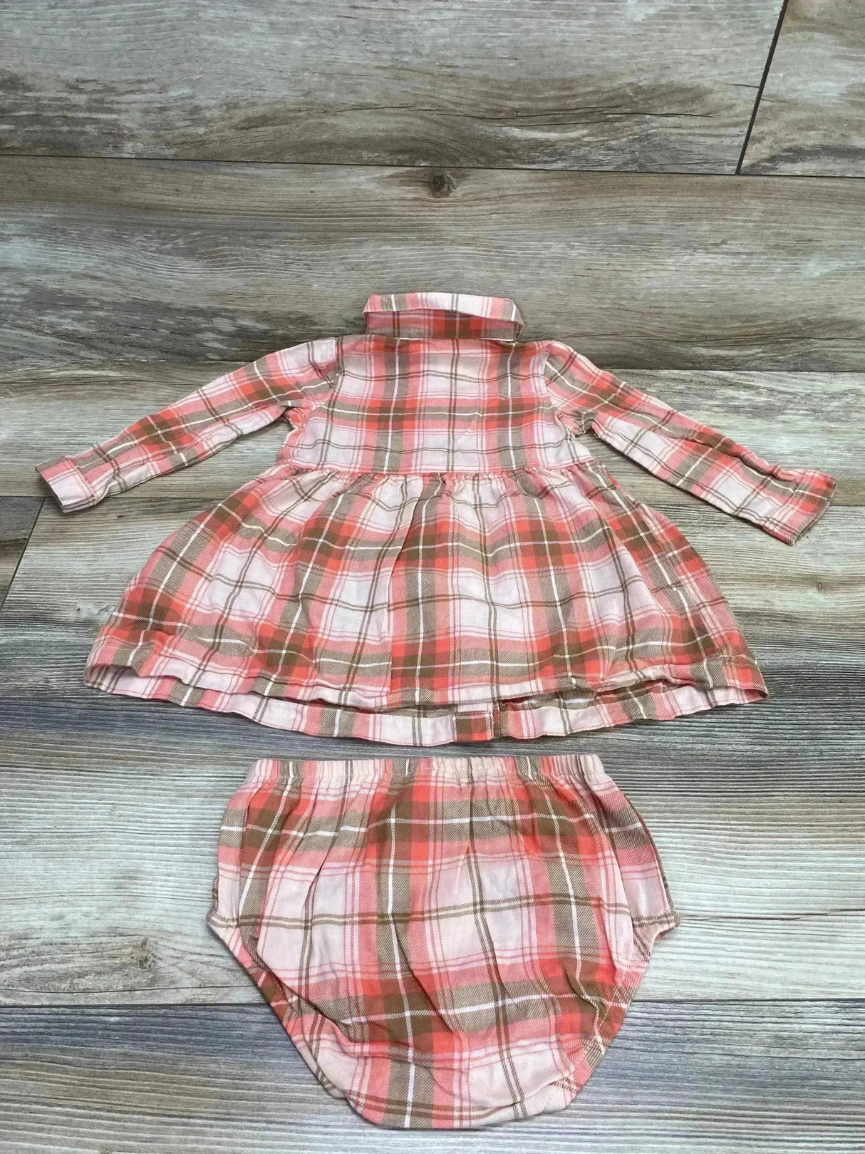 Flat lay of Carter's pink-brown plaid long-sleeve baby dress with gathered skirt and matching bloomers on wood background