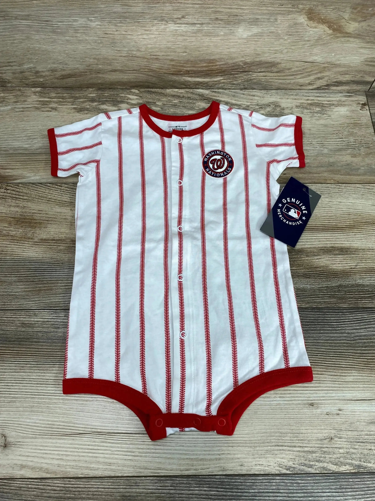 Flat lay of Washington Nationals baby creeper size 24M with red pinstripes, logo patch and snap closures on wood background