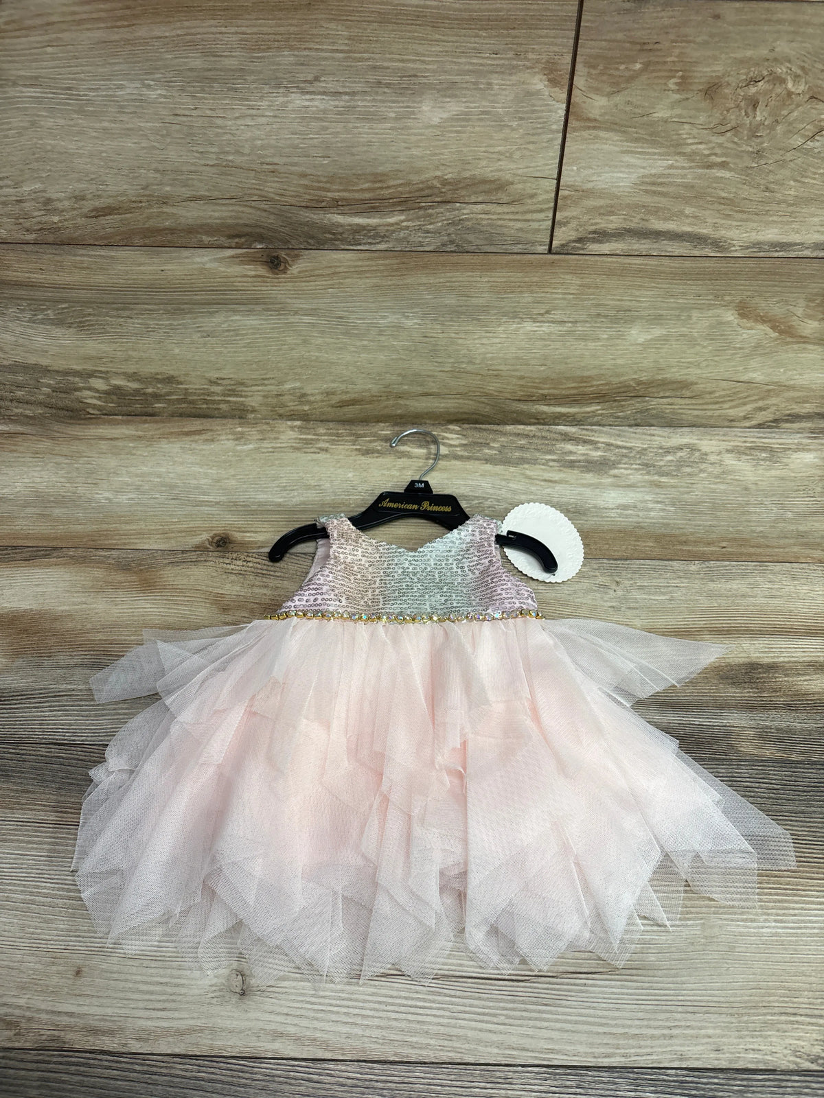 Front view of a pink size 3M sleeveless sequin dress and bloomers showcasing a layered tulle skirt on a hanger
