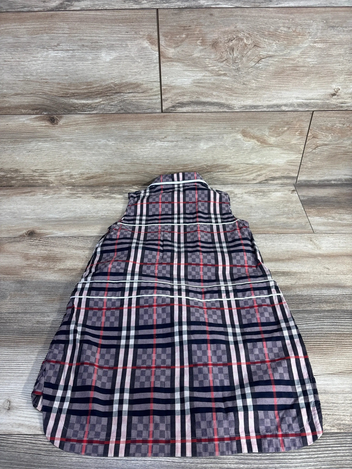 Flat lay of Burberry Carlotta sleeveless collared dress (4T) showing multicolor checkerboard pattern on light wood background