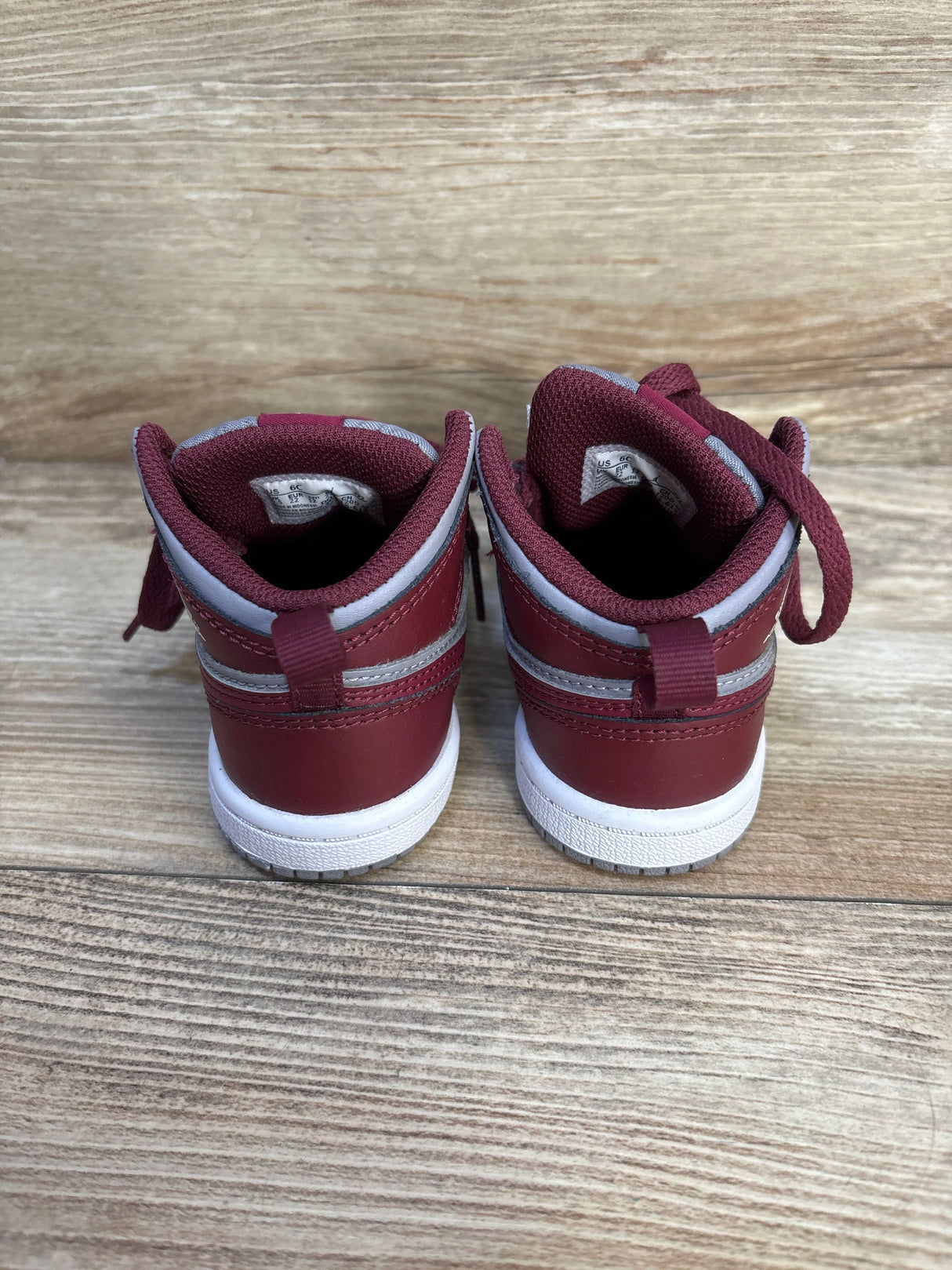 Back view of maroon and gray toddler sneakers on wood background