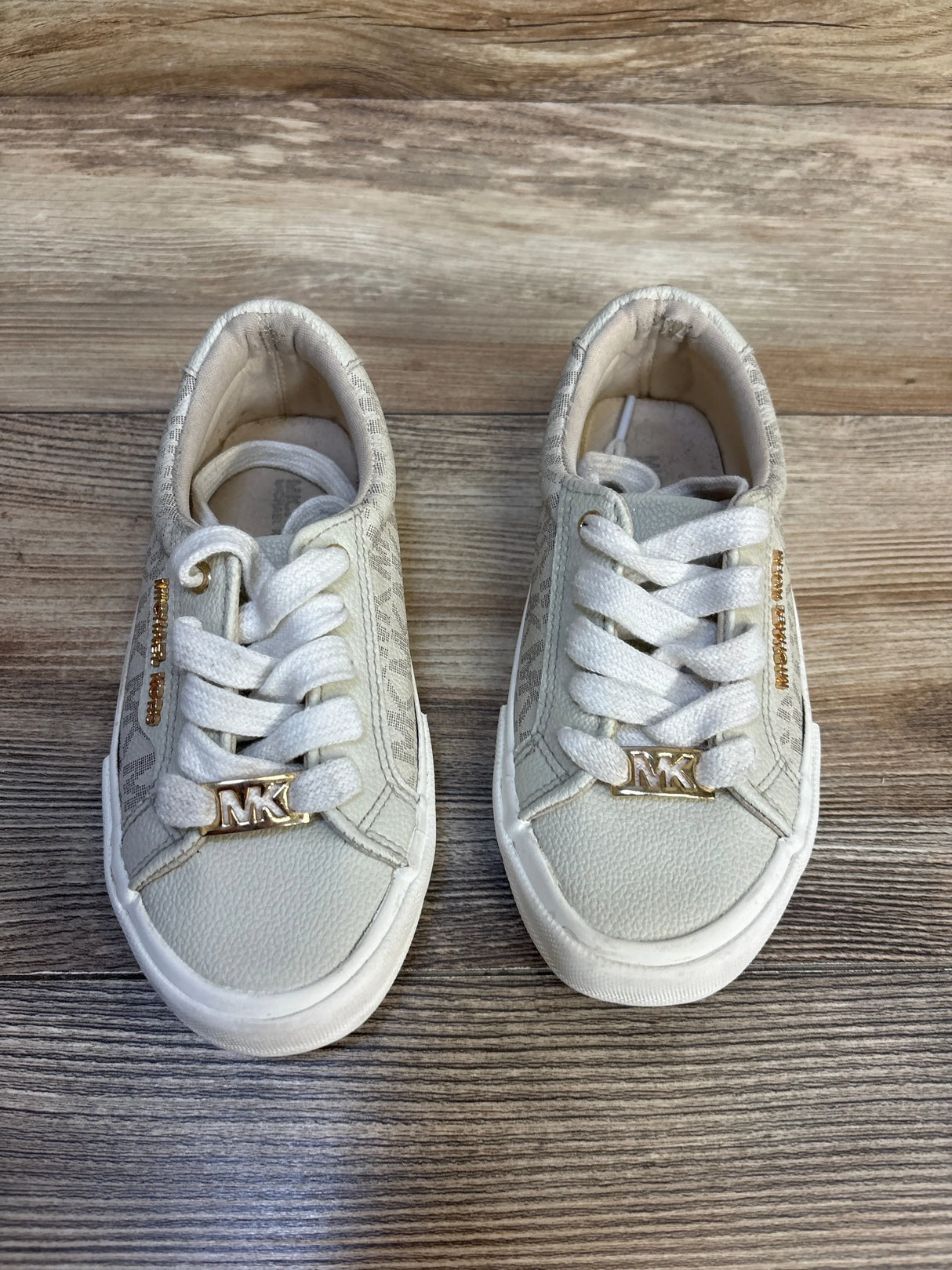 White kids' sneakers with gold MK logo, lace-up design, on wood floor