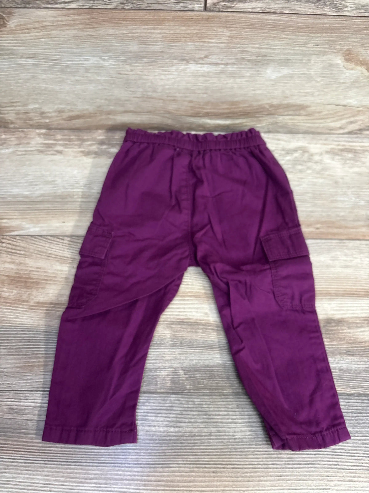 Purple toddler cargo pants with elastic waistband on wooden floor background
