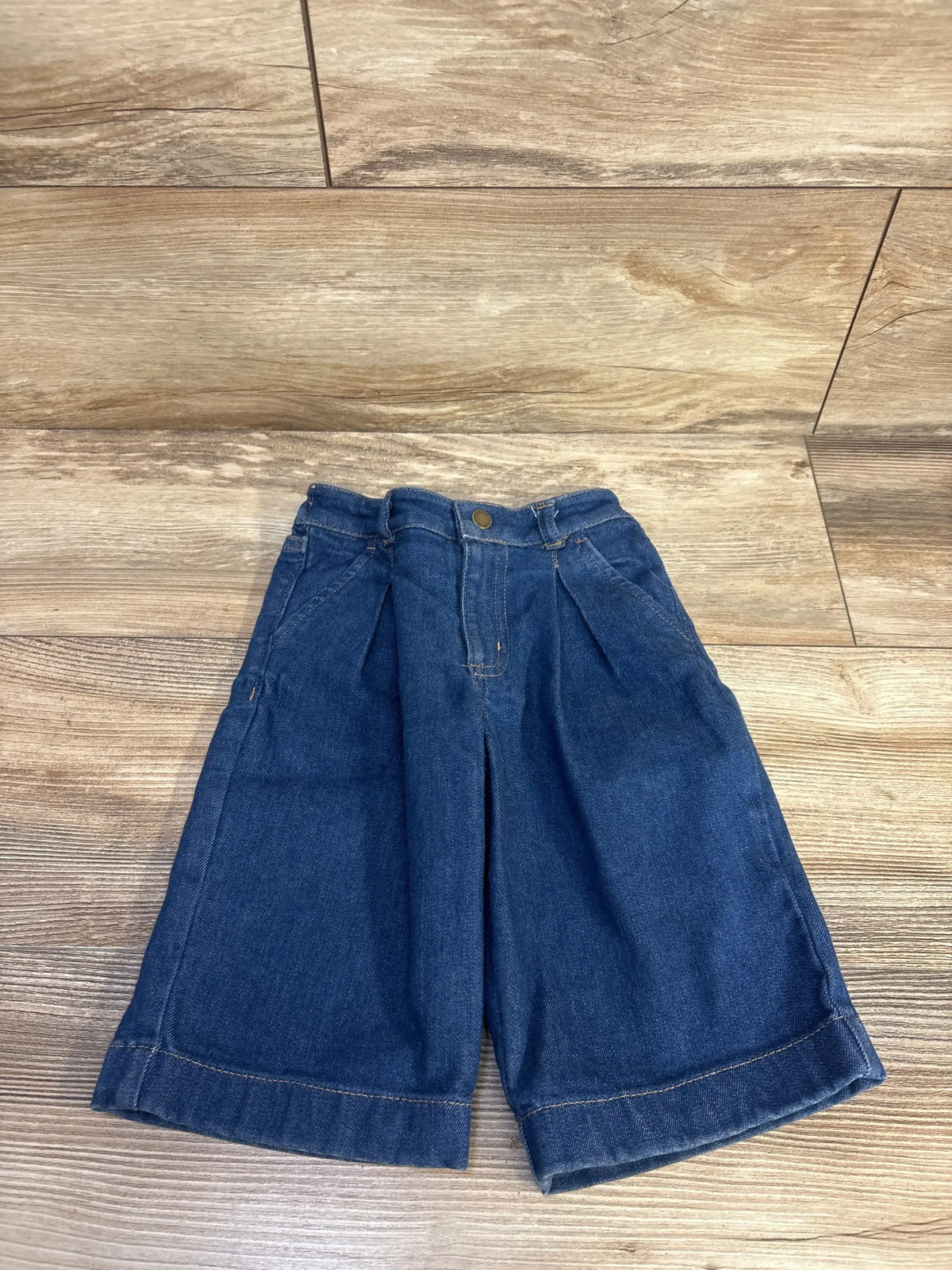 Flat-lay front view of Jack denim pleated wide leg jean showing front pleats and cuffed wide legs on wood floor background