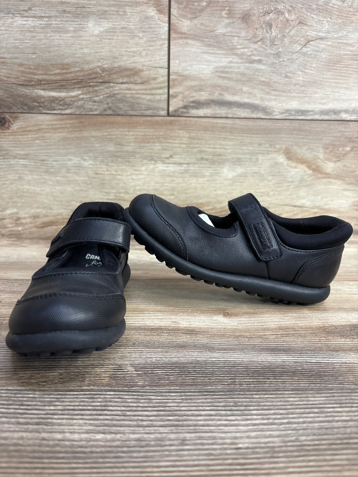 Black toddler Mary Jane shoes with Velcro straps on wood background