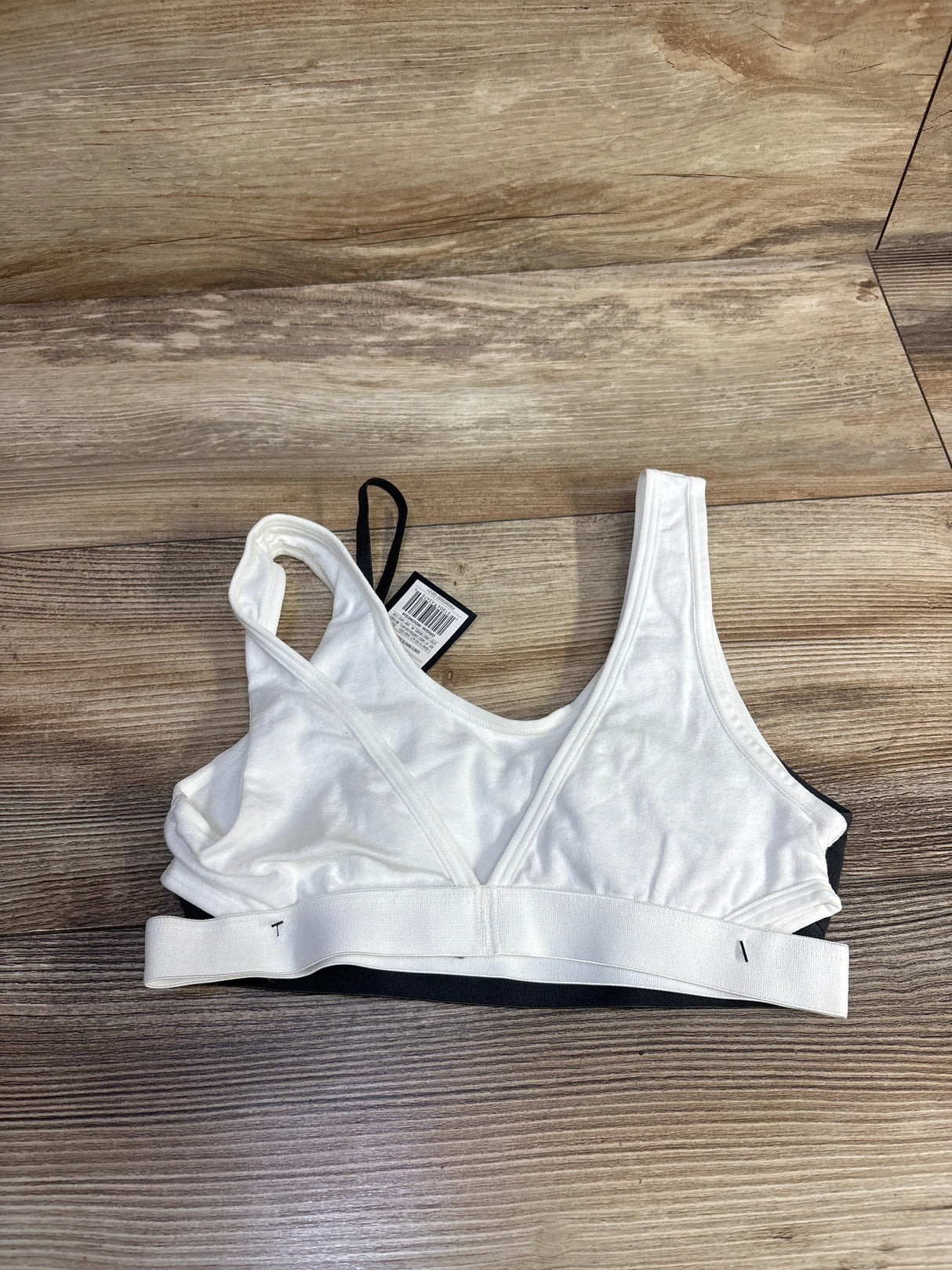 White sports bra with tag on wooden floor, adjustable strap detail visible