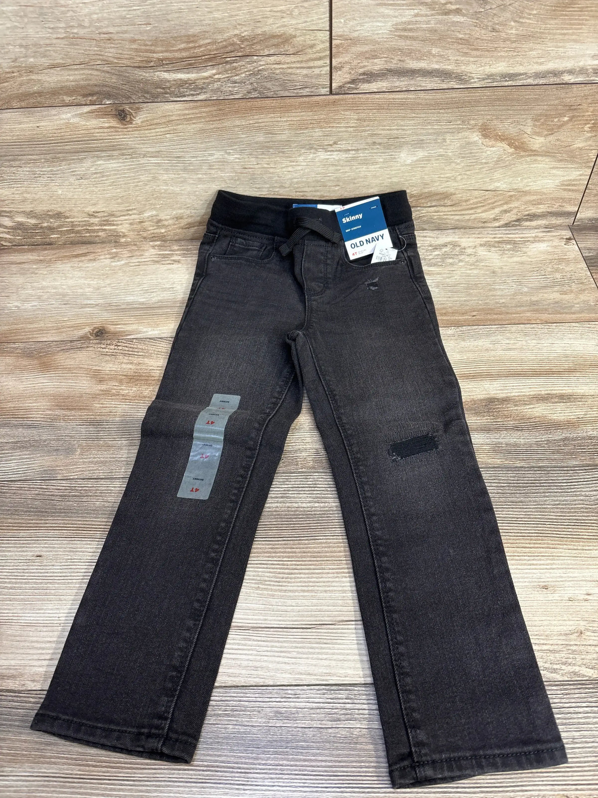 Old Navy black skinny jeans for kids with tags, displayed on wood floor