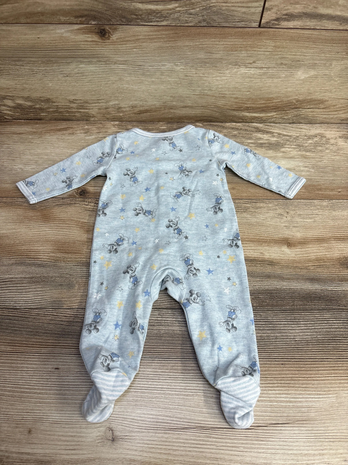 Gray baby footed sleeper with cartoon mouse and star print, long sleeves, on wood background