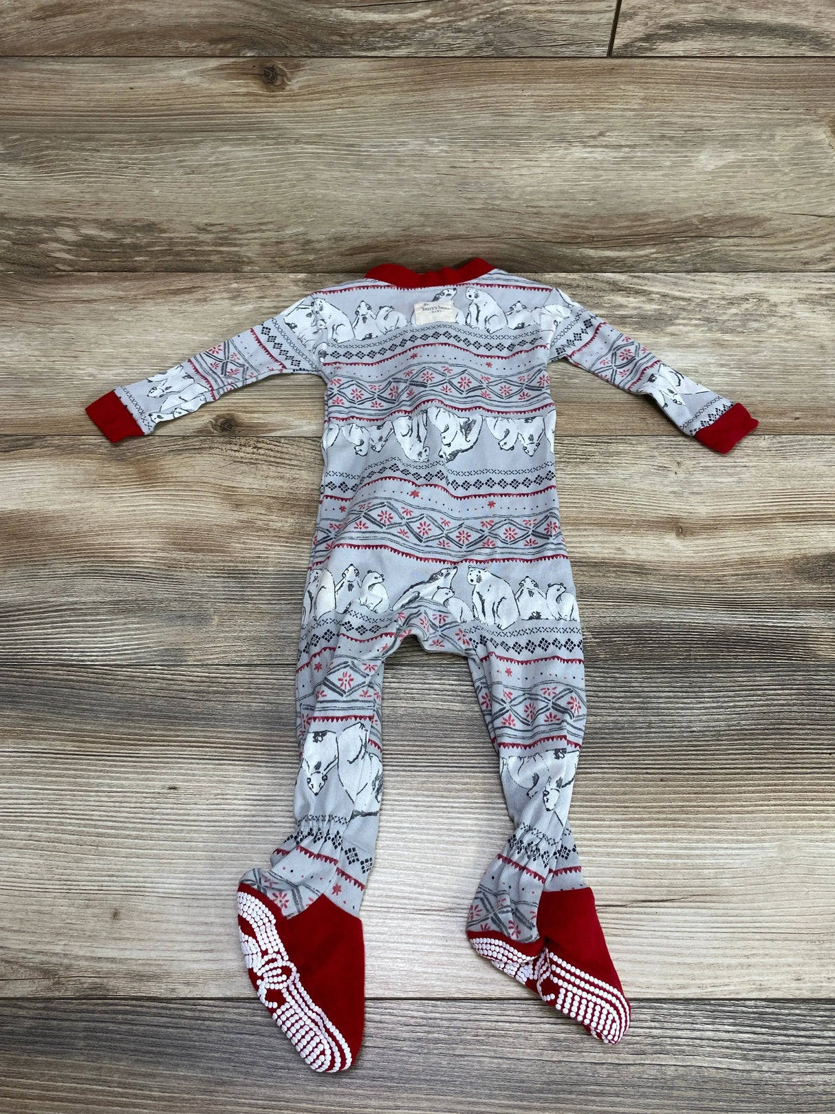 Flat lay of Burts Bees Baby sleeper with gray polar bear print, red cuffs and grippy red foot soles on wood background