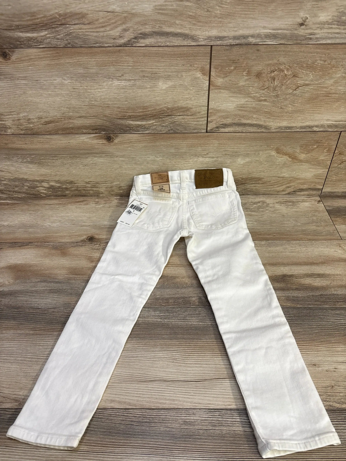 Front view of white Ralph Lauren Sullivan slim stretch jeans in size 5T showcasing five-pocket styling with a wood floor background