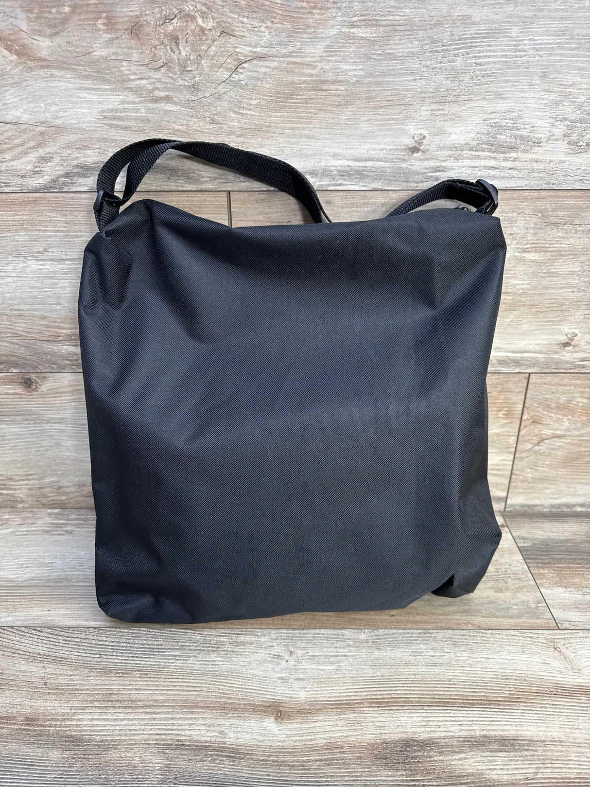Front view of Matriarch Pregnancy Support maternity belt packed in its black storage bag showing shoulder strap on wood floor background