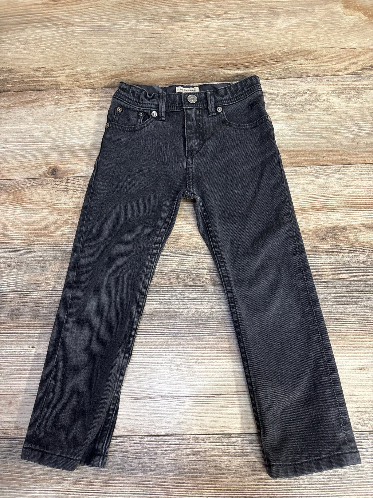 Flat lay of black Burberry toddler jeans (4T) showing straight legs, five-pocket styling and elastic waist on wood background