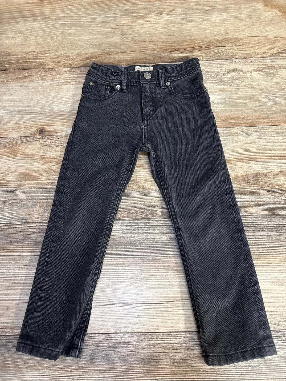Flat lay of black Burberry toddler jeans (4T) showing straight legs, five-pocket styling and elastic waist on wood background