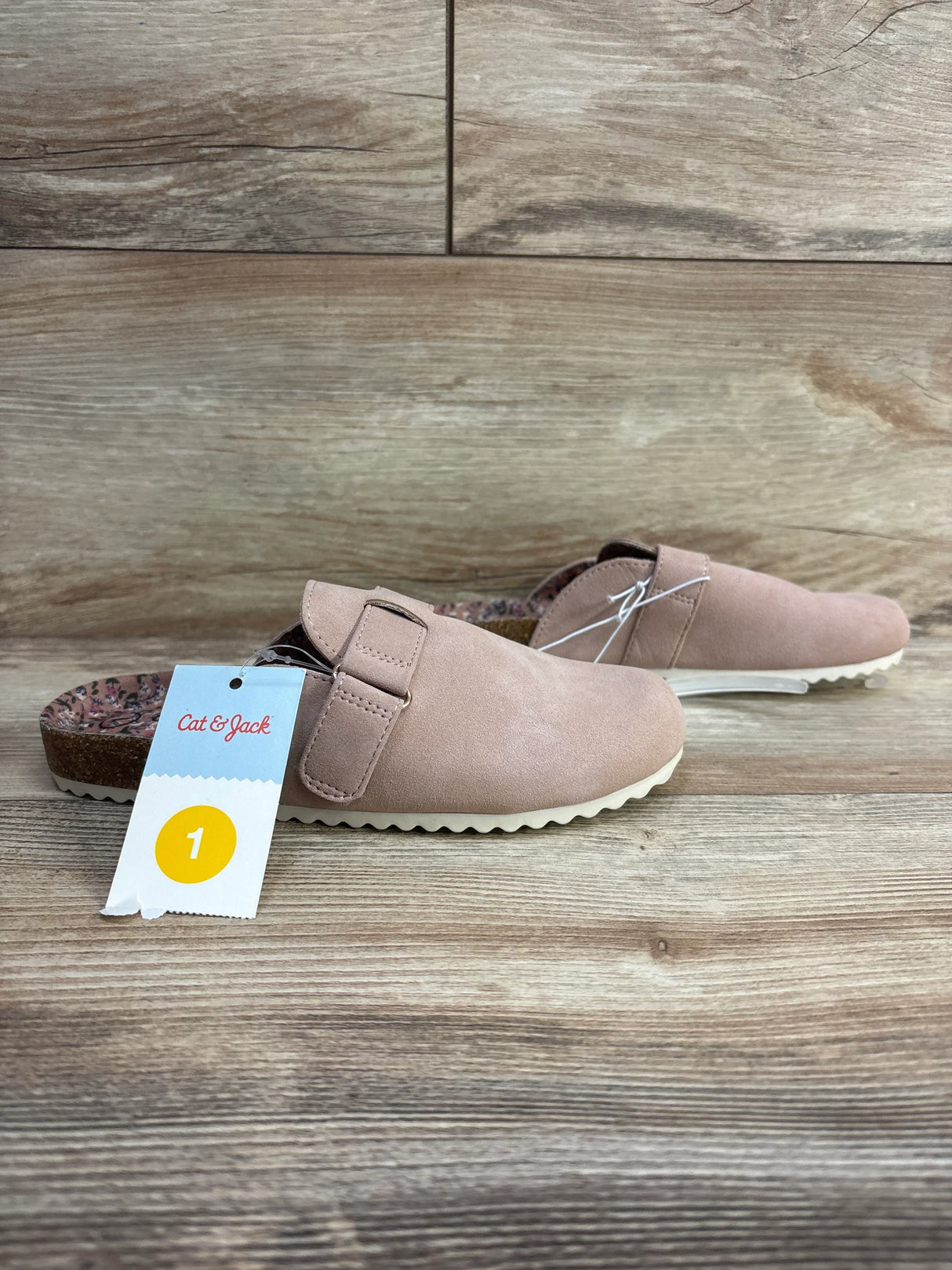 Pair of pink Cat & Jack slip-on clogs with adjustable strap and floral insole on wooden surface