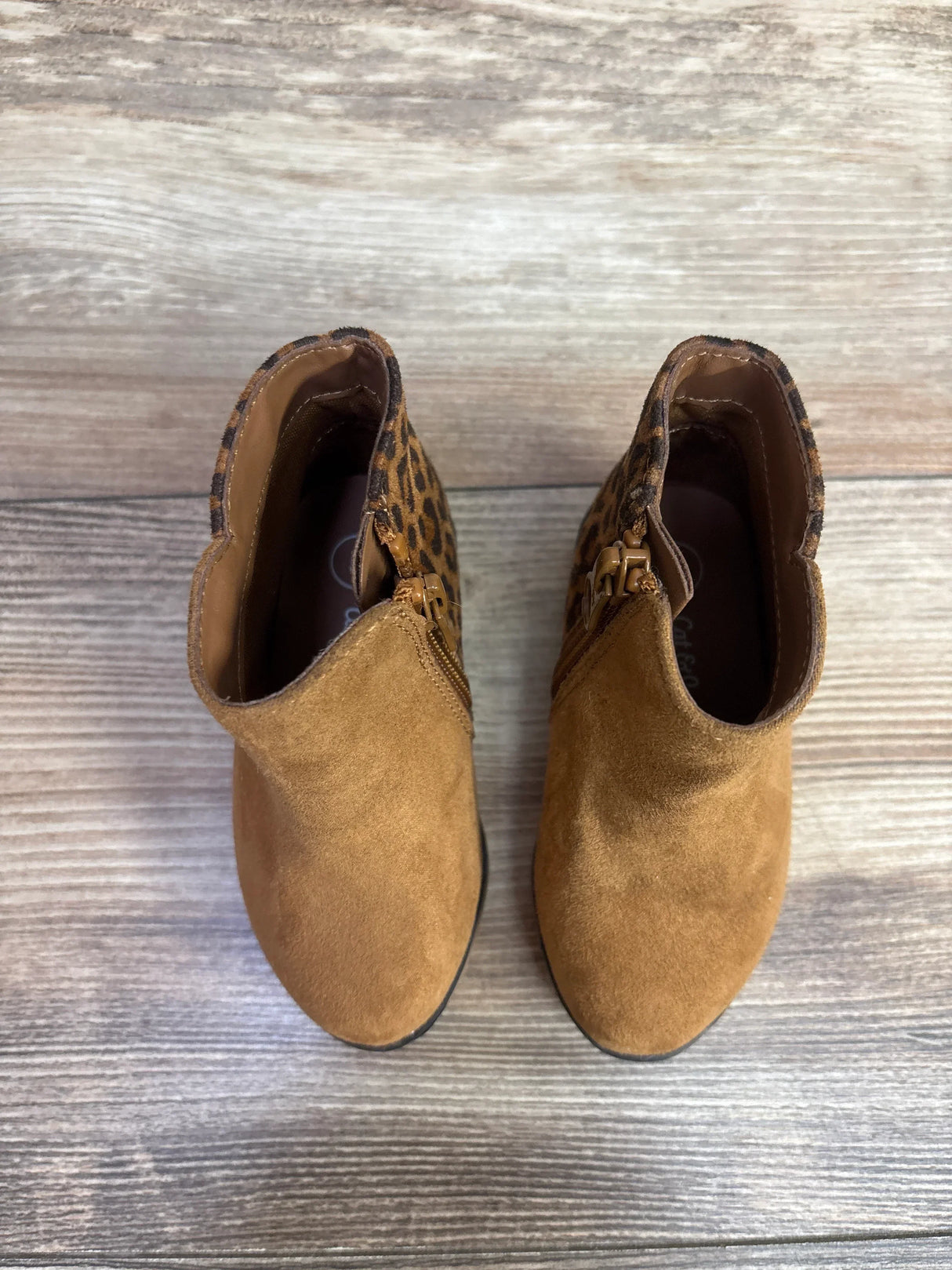 Pair of toddler brown suede ankle boots with leopard print accents and side zippers on wooden floor