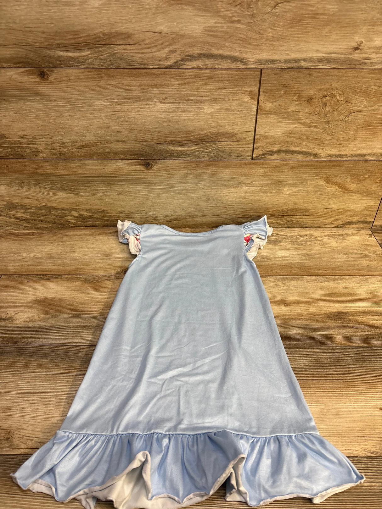 Flat-lay of Disney Aristocats Marie toddler nightgown showing light blue fabric, ruffled hem and flutter sleeves on wood background