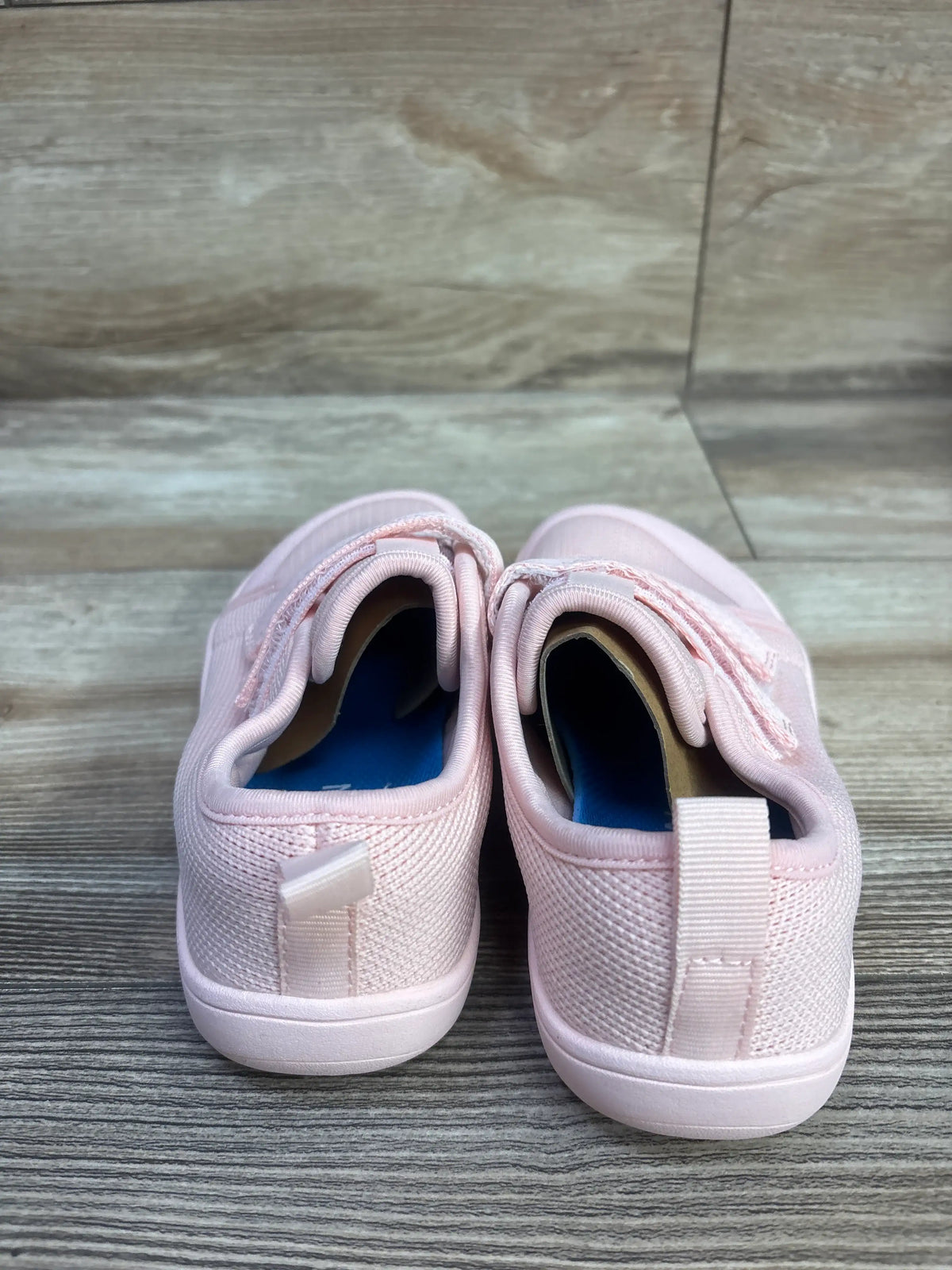 Rear view of pink NEW WHITIN wide barefoot sneakers size 13C showing pull tabs and textured uppers on a wood look floor