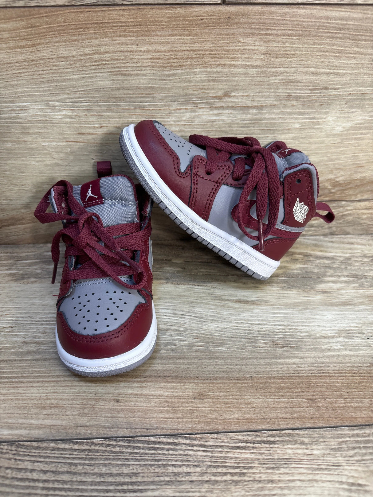 Pair of maroon and gray toddler high-top sneakers on wood background