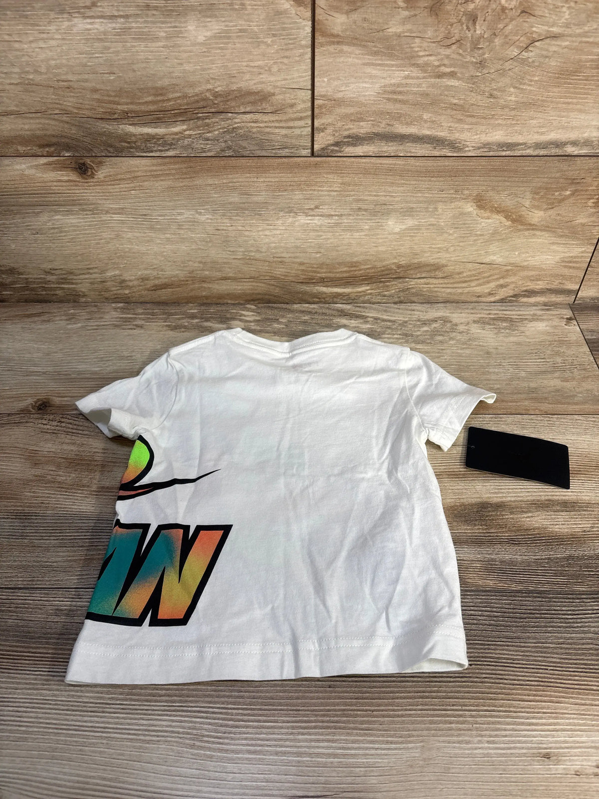 Front view of white Jordan Jumpman shirt in toddler size 2T showcasing a colorful Jumpman logo on a wood background