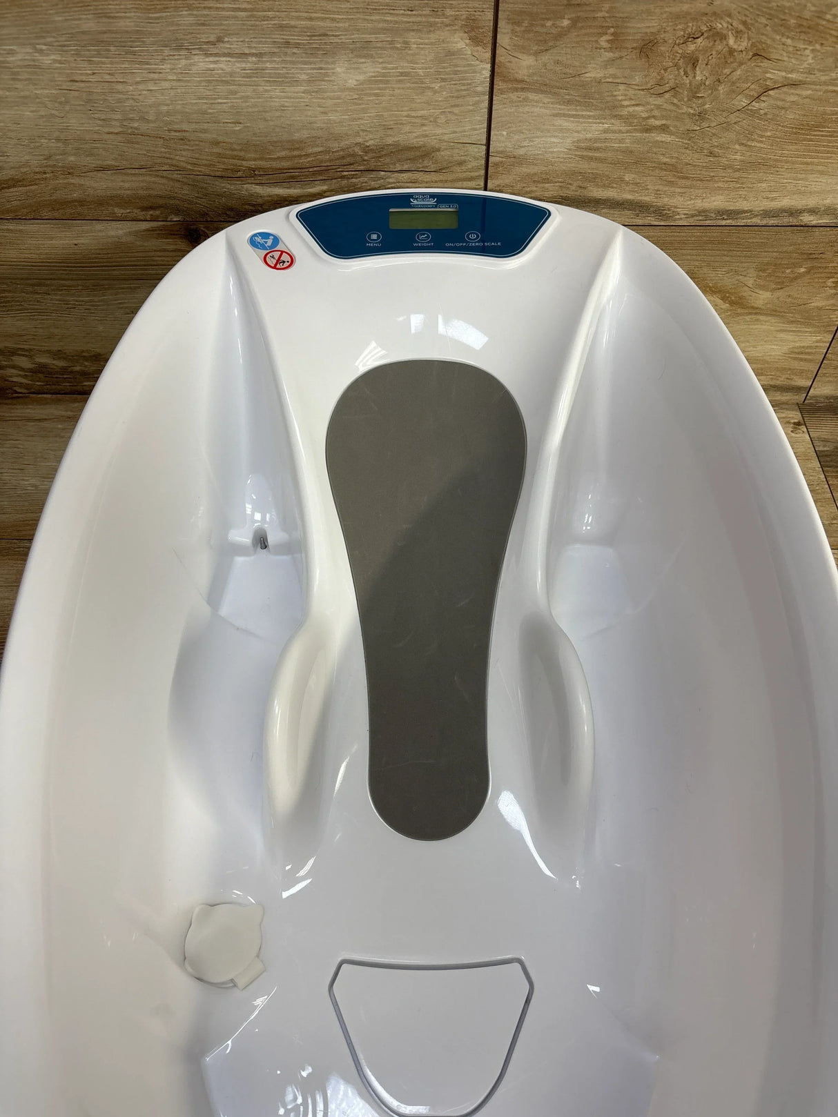 White baby bathtub with digital scale on wood floor background, ergonomic design