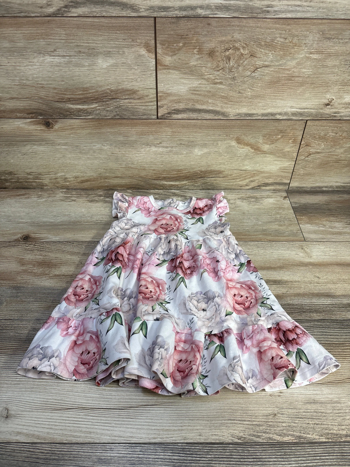 Front view of Sofia Mila pink floral sleeveless dress showcasing ruffled hem on a wood floor