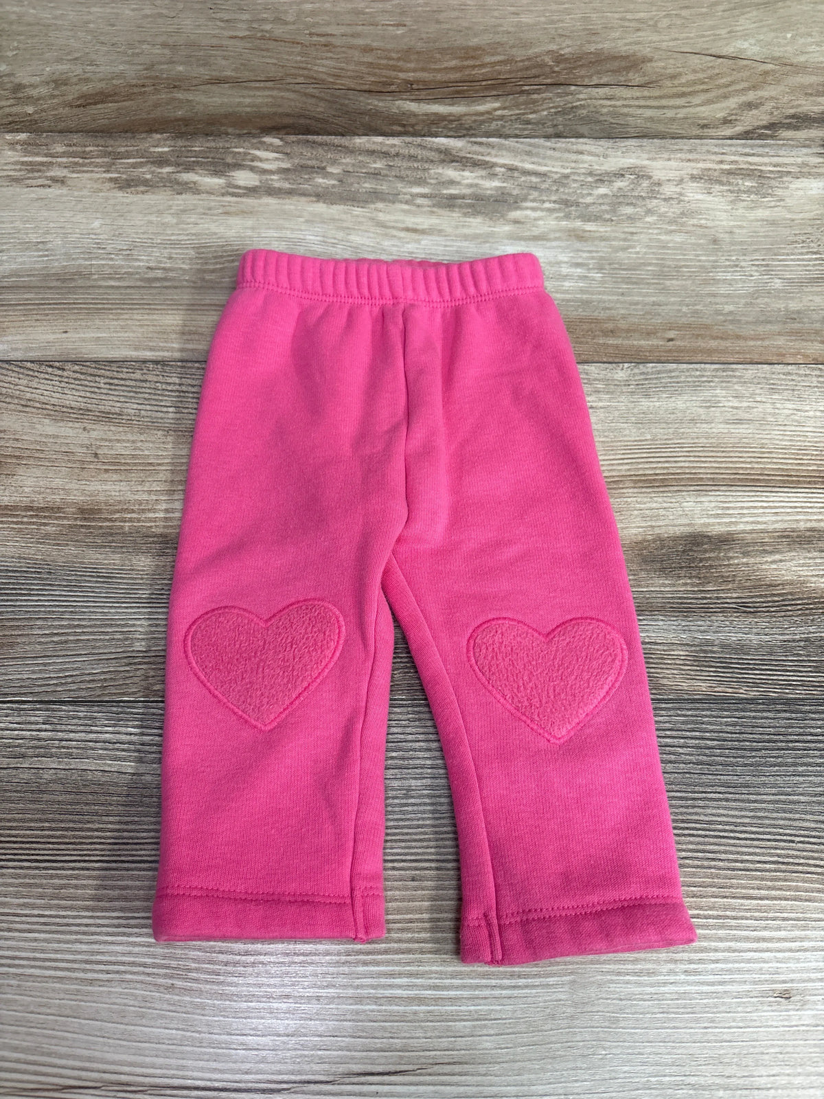 Old Navy baby pink pull-on pants with heart-shaped knee patches on a wooden background