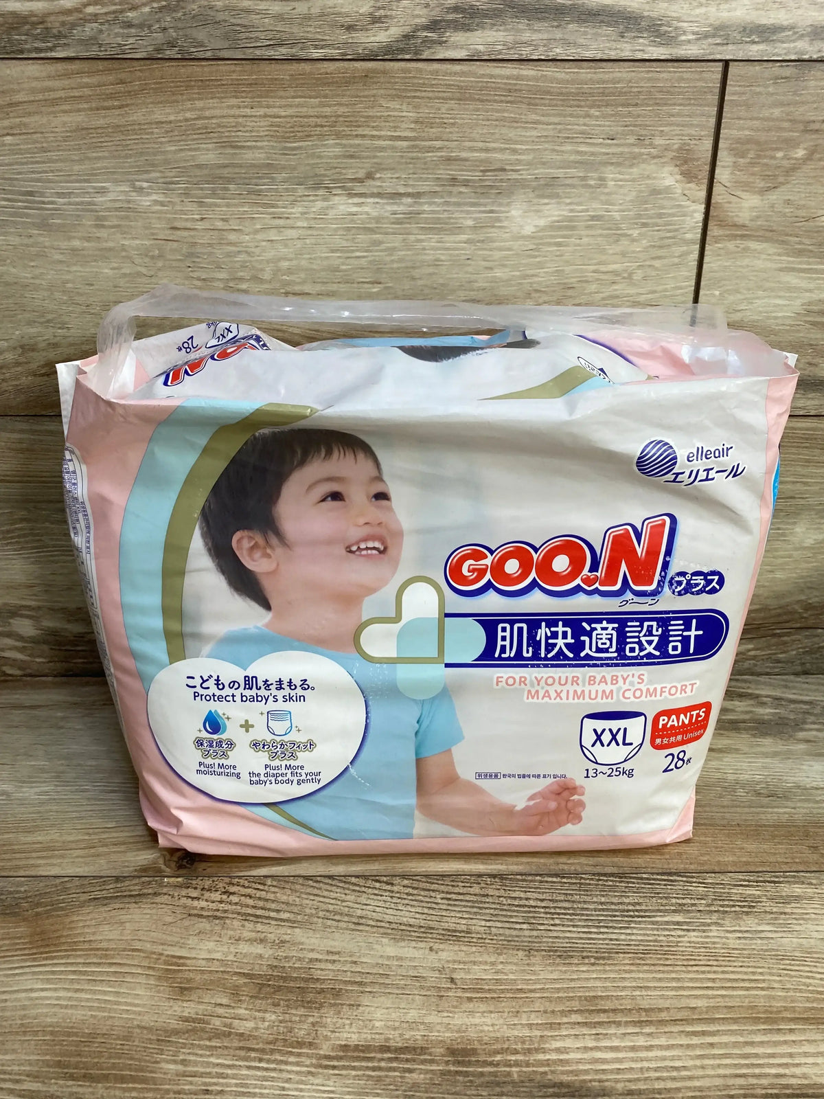 Front view of Elleair GOO.N Plus baby pull-up diaper pants pack, XXL (13–25 kg), 28 count, smiling toddler on wood background