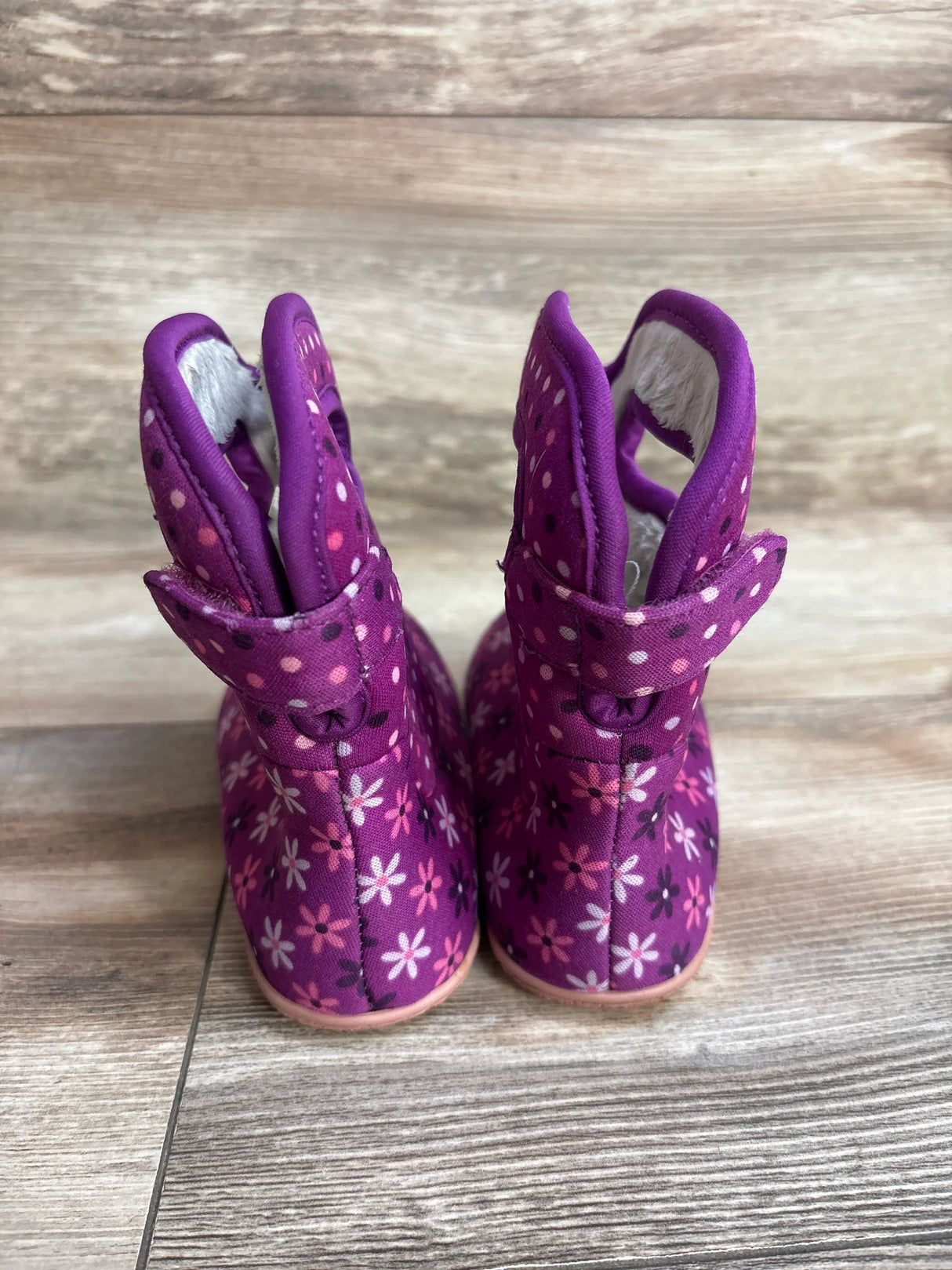 Purple baby boots with floral and polka dot patterns on wood floor