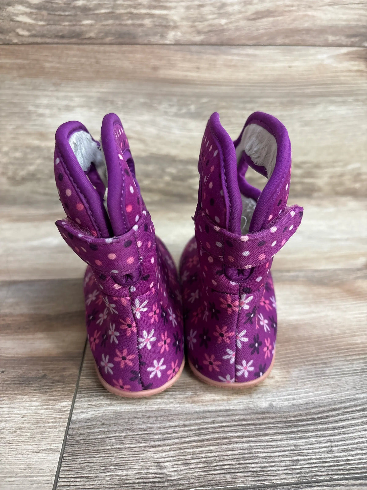 Rear view of BOGS II rainboots size 8C in purple showing floral and polka dot pattern and Velcro strap on wood floor