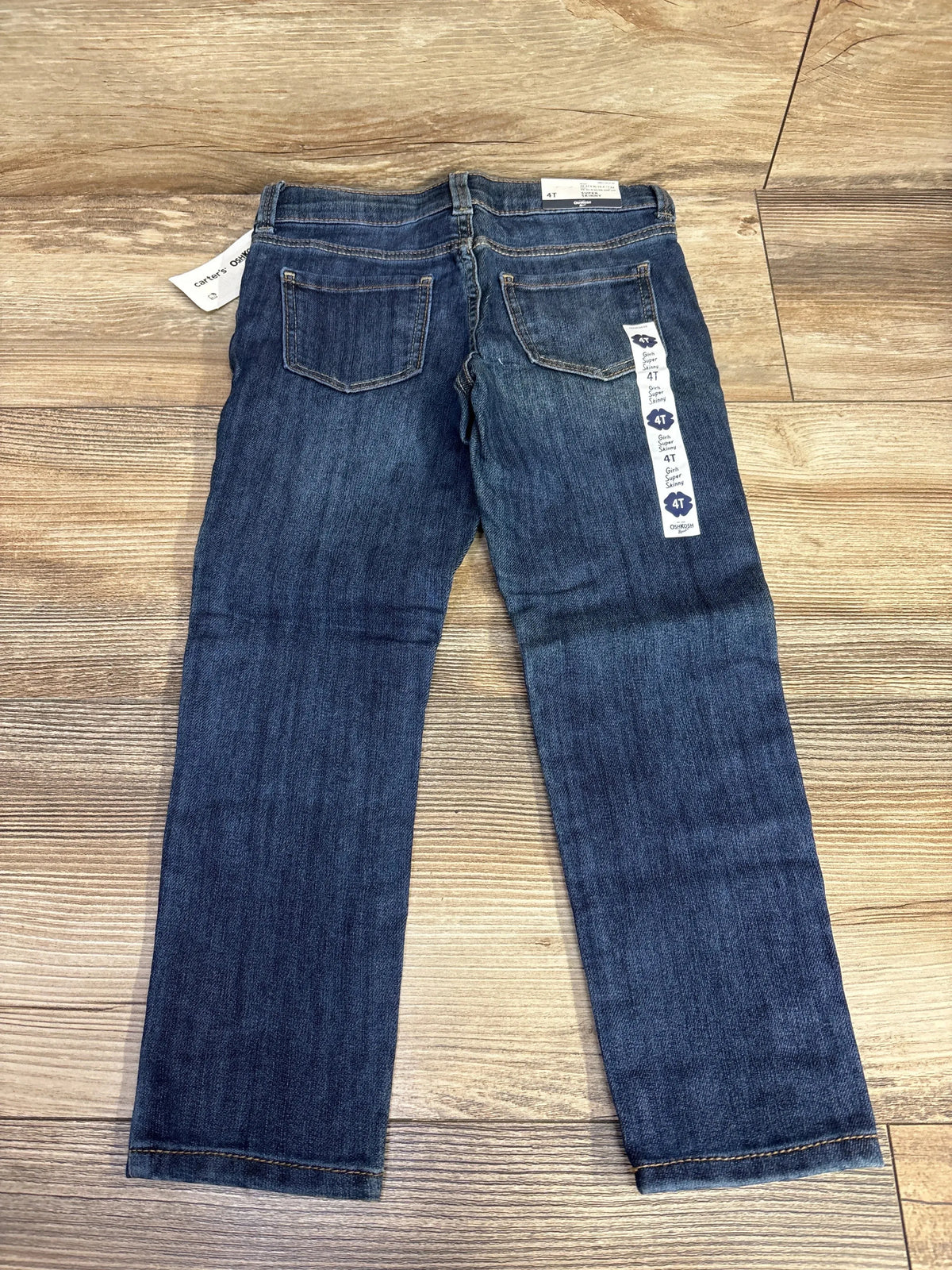 Back view of toddler blue denim jeans size 4T on wooden floor, two back pockets visible.