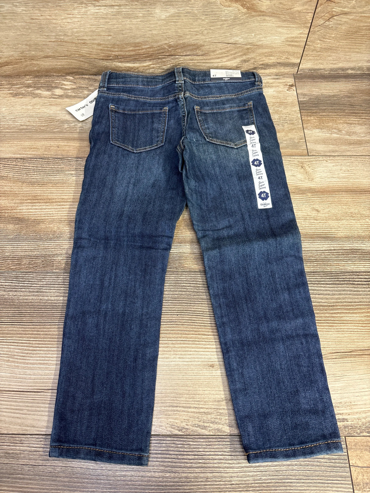 Back view of toddler blue denim jeans size 4T on wooden floor, two back pockets visible.